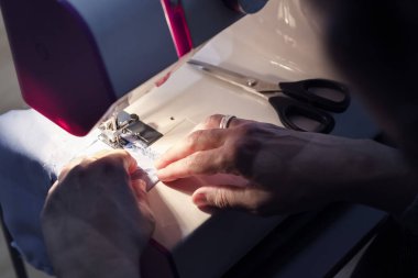 Dikiş makinesinde çalışan kadın terzinin elleri, el işi ve hobiler, karanlık tarz ve seçici odaklanma kavramı.