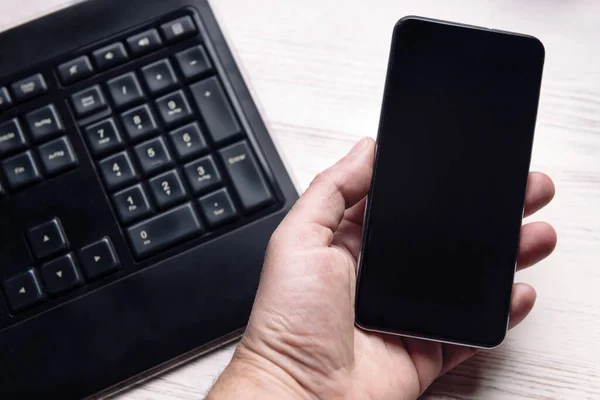 Hand Hält Ein Smartphone Mit Leerem Bildschirm Auf Weißem Holztisch — Stockfoto