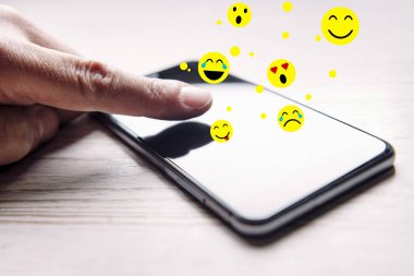 Beyaz ahşap masa, sosyal medya ve iletişim konsepti üzerinde ortaya çıkan bir telefonun ekranına dokunmak, seçici odaklanma