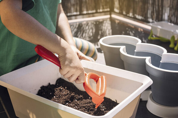 detail of a child hands preparing the soil before putting it in pots for planting, hobbies at home, sustainable and ecological lifestyle concept