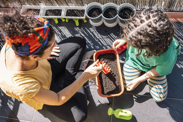top view of an unrecognizable child preparing the gardening sand with her mother to plant in a planter, hobbies at home, sustainable and ecological lifestyle concept