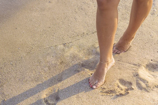 woman feet walking on the wet sand of the beach, concept of glamour and summer holidays