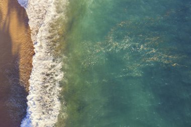 Turkuaz deniz suyu ve dalga köpüğüyle güzel sahil manzarası, metin için alanı kopyala