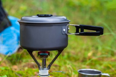 Melon şapkalı bir ocakta dağ yürüyüşünde yemek pişirmek. Arka planda yeşil çimen. Stok fotoğrafı