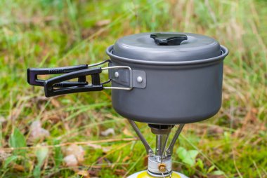 Melon şapkalı bir ocakta dağ yürüyüşünde yemek pişirmek. Arka planda yeşil çimen. Stok fotoğrafı