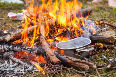 Yürüyüş sırasında şenlik ateşi yakılır. Doğada ateşte melon şapka pişirmek. Stok Fotoğrafı