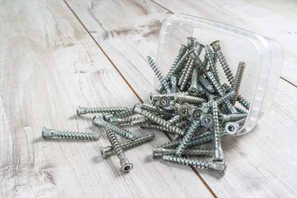 Group of Screw bolts for furniture assembling on wooden background. Stock photo.