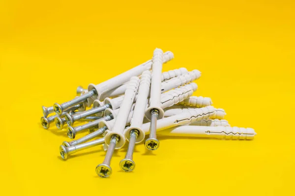 Group of Dowels and Nails on yellow background. Dowels for fastening in concrete. Stock photo.