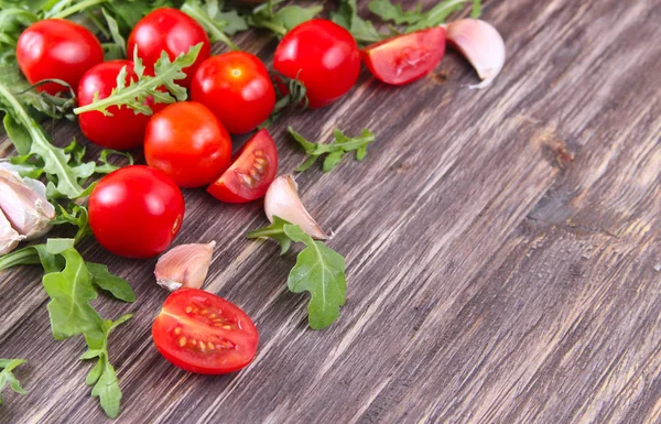 Tomates fraîches avec des feuilles de salade sur la table. Contexte . — Photo