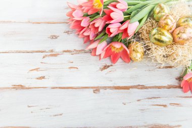 Altın Paskalya yumurtaları ve ışık arka plan üzerinde pembe laleler