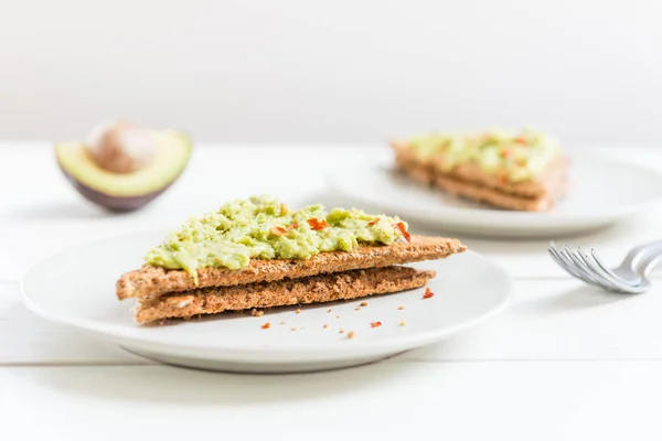 Grahamrostbröd bröd med mosad avokado och chili flingor — Stockfoto