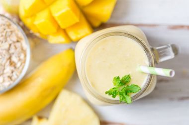 Mango, muz, ananas ve yulaf ezmesi Smoothie kavanozun içinde