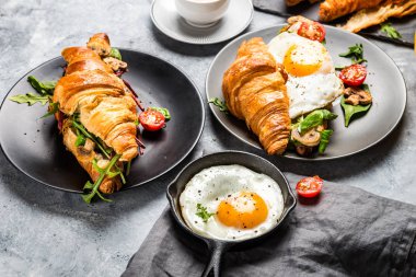 Kruvasan sandviç sahanda yumurta, salata yaprakları, ızgara Mushr ile