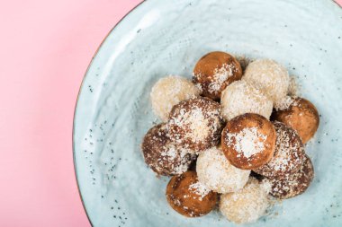 Çeşitli ev yapımı çiğ Vegan Truffles veya Hindistan cevizi ve limon, badem ve kakao, koyu çikolata ve fındık ezmesi pembe bir arka plan üzerinde gibi enerji topları