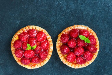 Nane yaprakları ile frambuazlı tart ve krema şeker koyu arka plan üzerinde ile kaplı