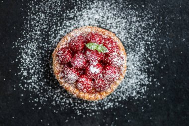 Nane yaprakları ile frambuazlı tart ve krema şeker koyu arka plan üzerinde ile kaplı