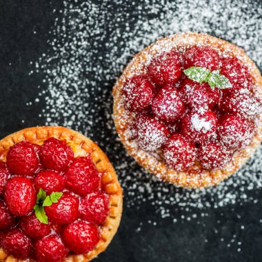 Nane yaprakları ile frambuazlı tart ve krema şeker koyu arka plan üzerinde ile kaplı