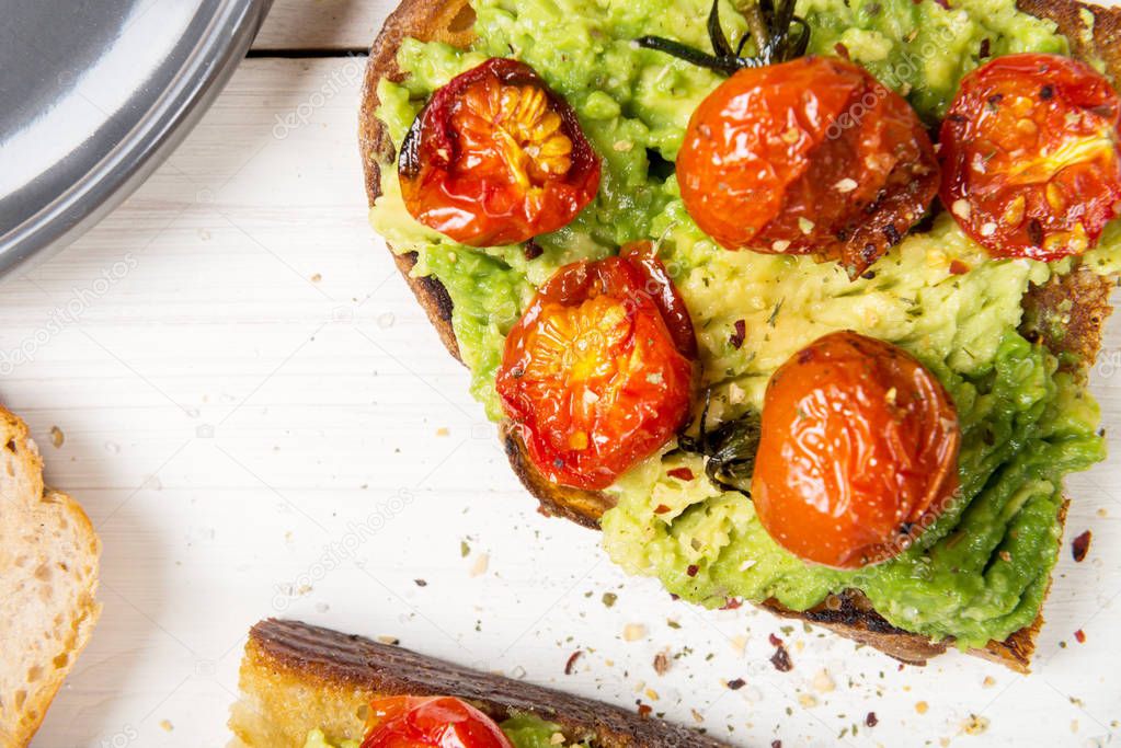 Healthy snack from white sourdough bread, such as avocado and roasted tomatoes toasts