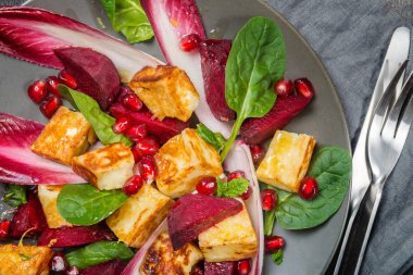 Nar, kırmızı pancar, kırmızı hindiba, ıspanak, nane ve Hellim salatası koyu gri arka plan