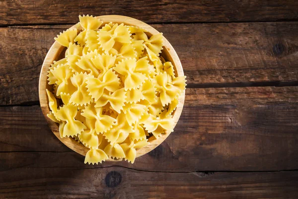 Farfalle di pasta cruda in ciotola di legno — Foto Stock