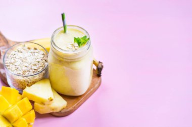 Mango, muz, ananas ve yulaf ezmesi Smoothie kavanozun içinde