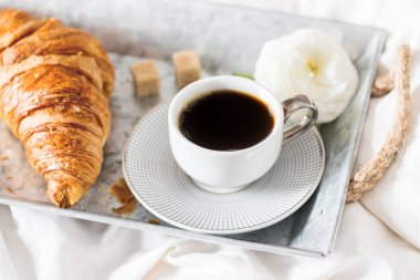 Taze kruvasan, fincan kahve ve tipik çiçekler. Kahvaltı