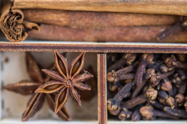 Kurutulmuş baharatlar, zencefil, nane, karanfil, biber pul, Kakuleden, yıldız anason, gibi çeşitli karanlık rustik ahşap zemin üzerine tarçın kutu
