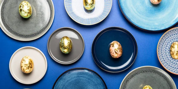 Piatti diversi con uova di Pasqua di colori pastello su sfondo blu — Foto Stock