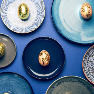 Mavi arkaplanda pastel renkli Paskalya yumurtaları ile farklı tabaklar