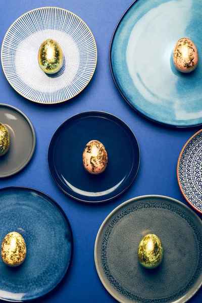 Piatti diversi con uova di Pasqua di colori pastello su sfondo blu — Foto Stock
