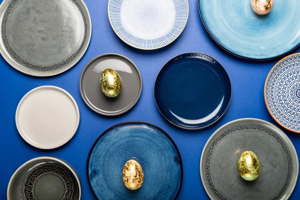 Olika tallrikar med påsk ägg av pastell färger på blå bakgrund — Stockfoto