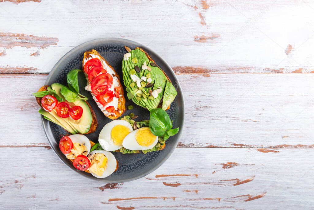 Sweet potato toasts with avocado, eggs, tomatoes and sesame seeds