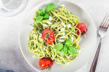 Ev yapımı pesto soslu makarna, kavrulmuş domates ve taze fesleğen yaprağı, vejetaryen yemeği.