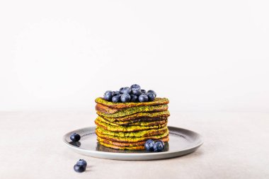 Ispanak, hindistan cevizi sütü, muz ve yabanmersinli yulaf ezmesinden yapılmış sağlıklı ve kolay çırpılmış yeşil krepler. Vejetaryen ve glütensiz kahvaltı.