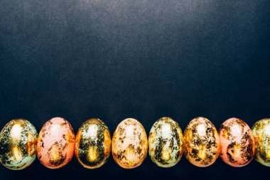 Siyah arkaplanda pastel renklerin doğal altın benekli paskalya yumurtaları. Mutlu Paskalya kartı konsepti, minimalist tasarım, kopyalama alanı