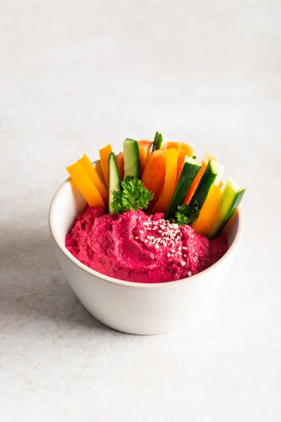 stock image Homemade Beetroot Hummus made from Chickpeas and Beetroot in White Bowl with Carrot and Cucumber Sticks, light grey background. Healthy Vegetarian Detox Snack