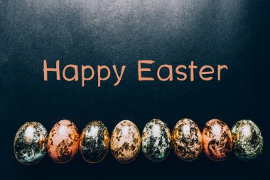 Doğal benekli pastel renkli Paskalya Yumurtaları ve siyah arkaplanda Mutlu Paskalya metinleri. Mutlu Paskalya kartı konsepti, minimalist tasarım, kopyalama alanı