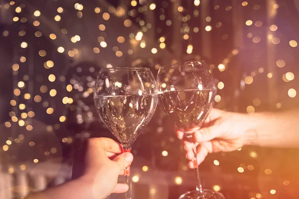 一位年轻的女士和一位男士拿着香槟酒庆祝新年 背景上美丽的圣诞彩灯 — 图库照片