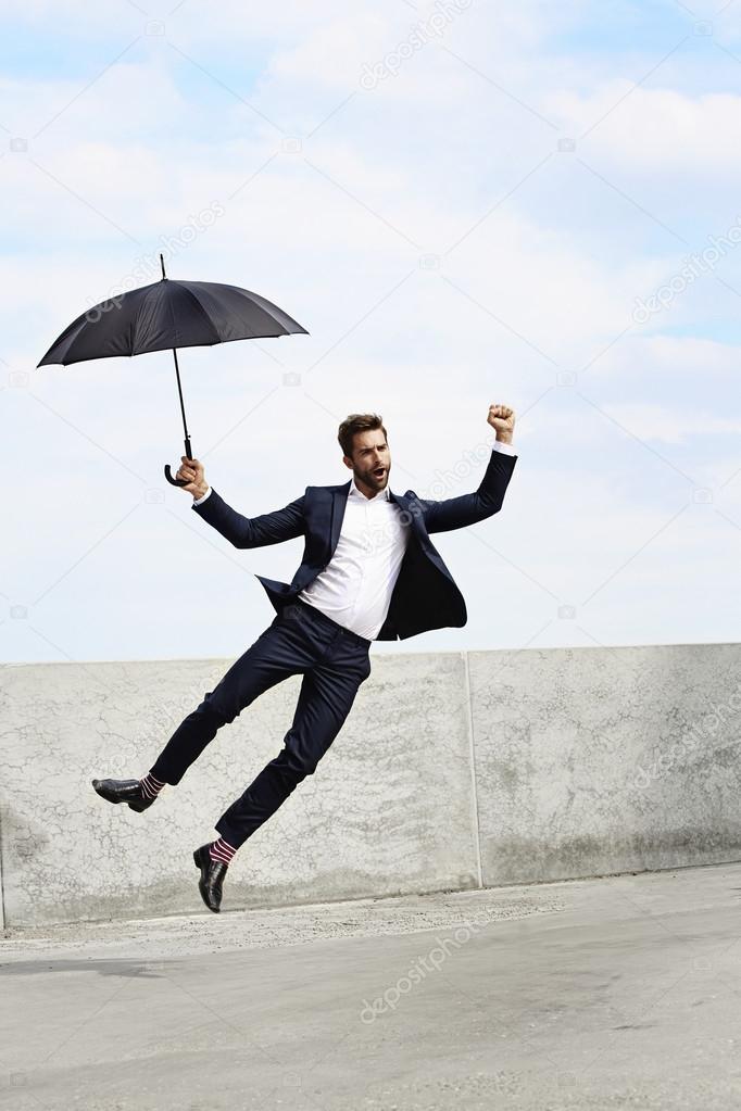 Ecstatic jumping businessman with umbrella