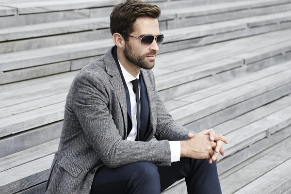 Empresario en gafas de sol sentado en la escalera — Foto de Stock