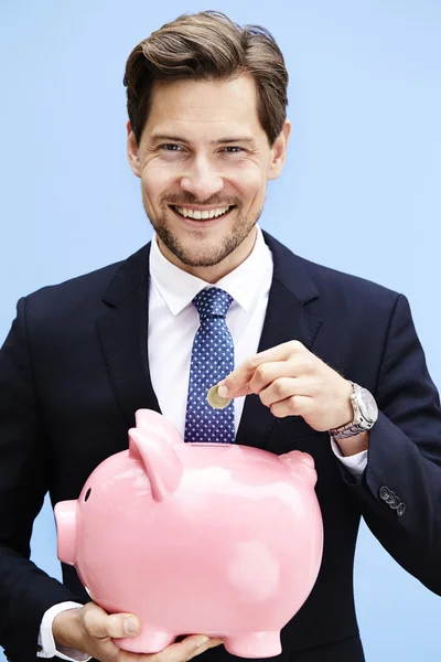 Geschäftsmann spart Geld in Sparschwein — Stockfoto