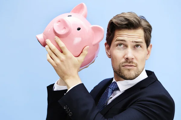 Geschäftsmann lauscht nach Bargeld im Sparschwein — Stockfoto