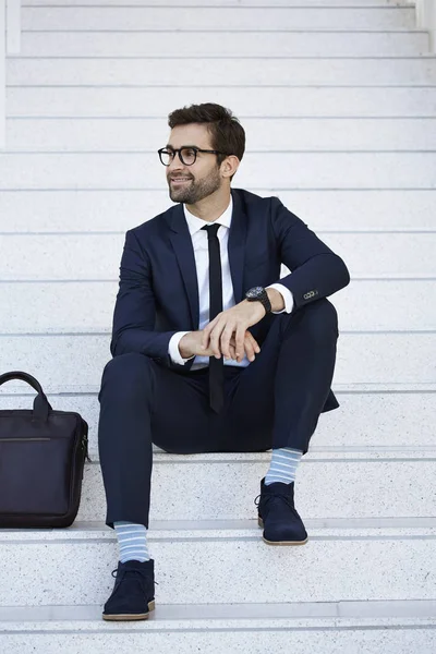 Smiling businessman sitting on steps — Stock Photo, Image