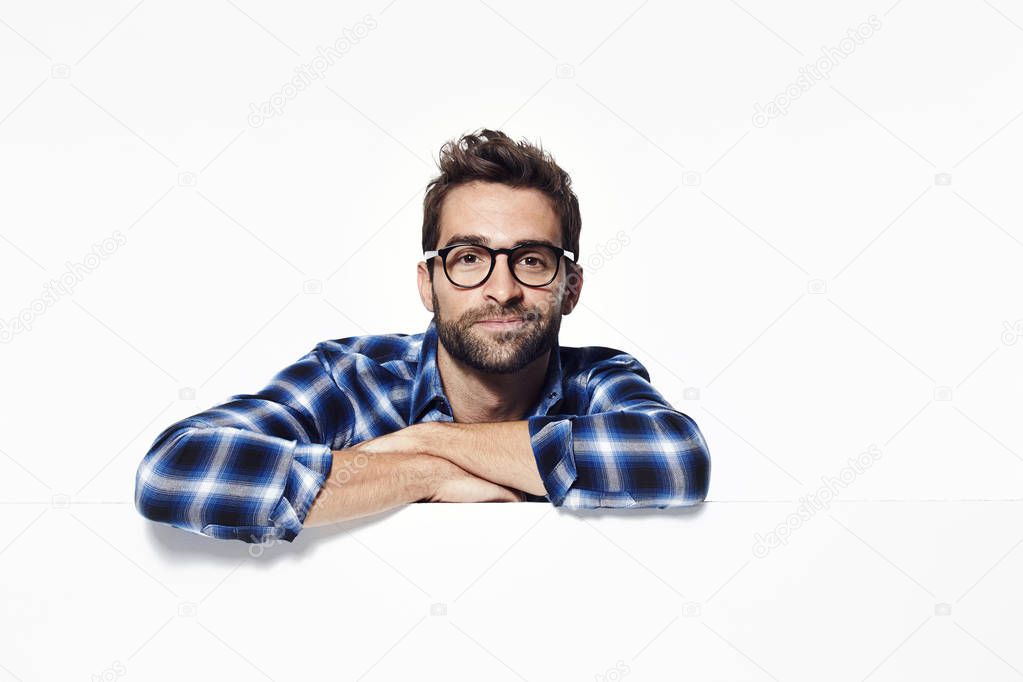 Handsome man leaning on white surface