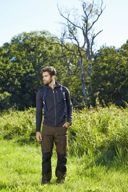 Çayır üzerinde duran uzun yürüyüşe çıkan kimse
