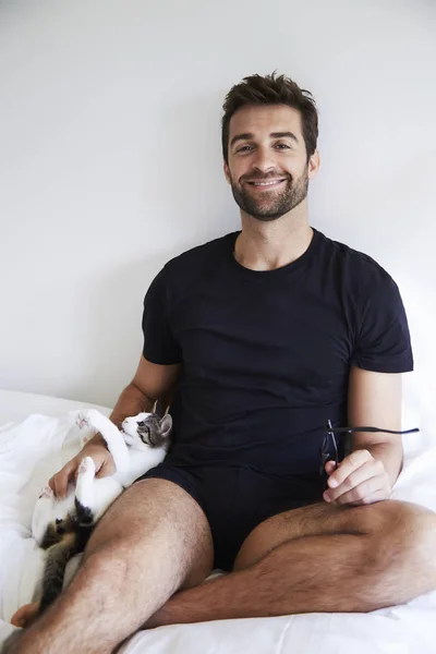 Uomo seduto a letto con gatto — Foto Stock