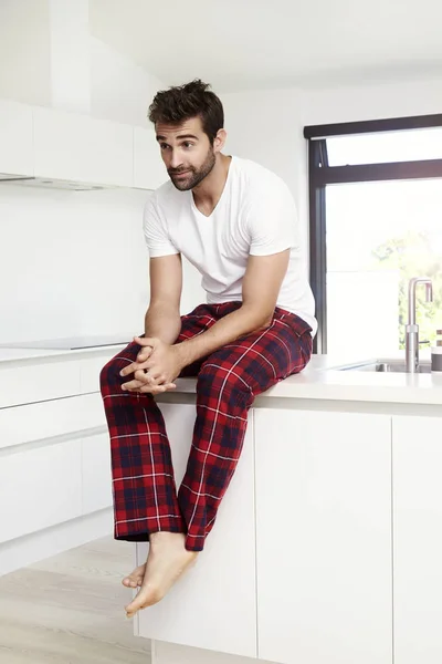 Man in pajamas sitting in kitchen — Stock Photo, Image