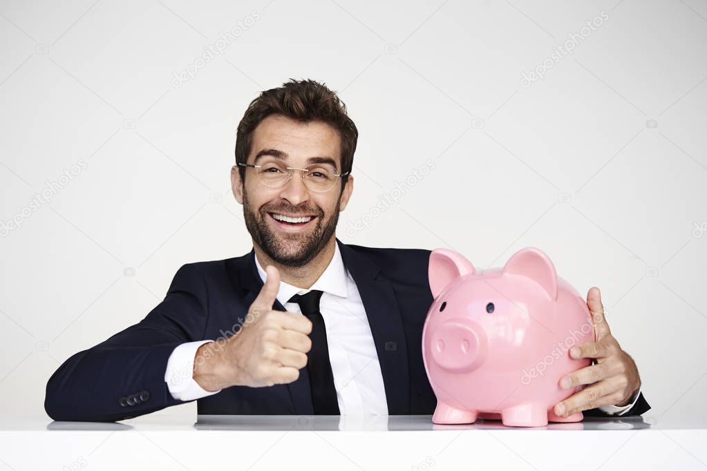 Businessman with thumb up for piggybank