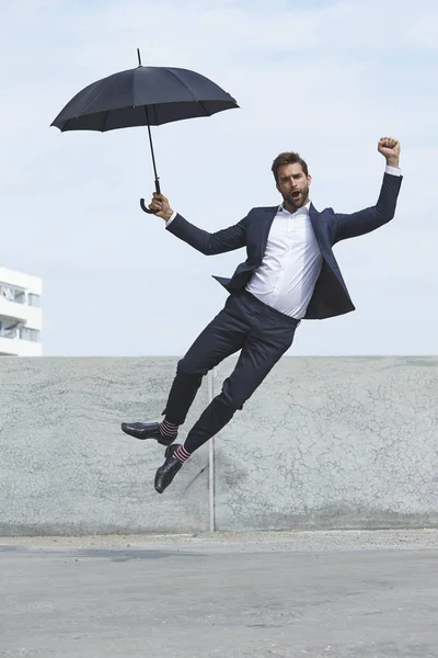 Empresario saltando con paraguas —  Fotos de Stock