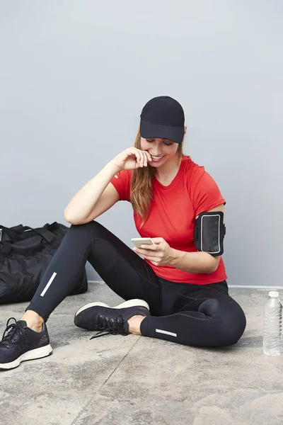 Lachende atletische vrouw met mobiele telefoon — Stockfoto